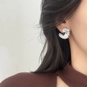 Elegant silver wing-shaped stud earring with textured metal stripes on a female model