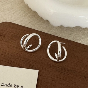 Detailed close-up of silver geometric layered hoop earrings on an aesthetic background