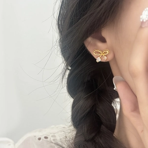 Eleganti orecchini a fiocco dorati con zirconi a forma di cuore indossati da una modella