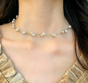 Detail of elegant French-style pearl necklace featuring small and large pearls on a chain