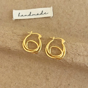 Detail view of gold layered twisted hoop earrings on handmade textured background