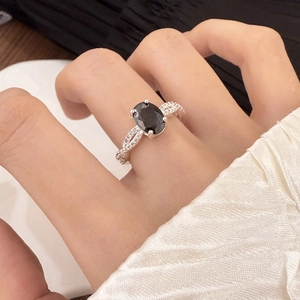 Macro shot of silver ring featuring a large oval black gemstone and micro-pave diamonds