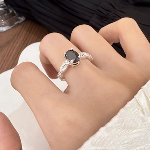 Detailed view of a silver ring with large oval black gemstone and twisted zircon band