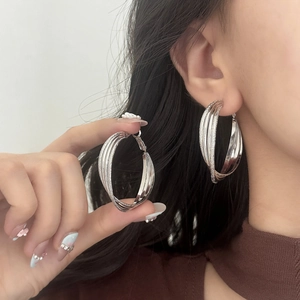 Close-up of silver multi-layered Moebius hoop earrings featuring mixed matte and glossy textures