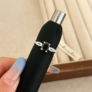 Detail of vintage silver ring with oval black gemstone and twisted pave diamond band