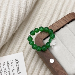 Elegant green chalcedony beaded ring with silver butterfly charm on display case