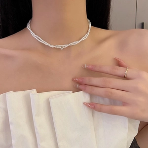 Elegant multi-layer pearl necklace and gold diamond ring worn by a model in white