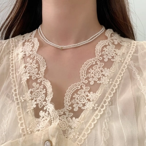 Elegant layered pearl choker necklace with a gold bead accent worn on model neck