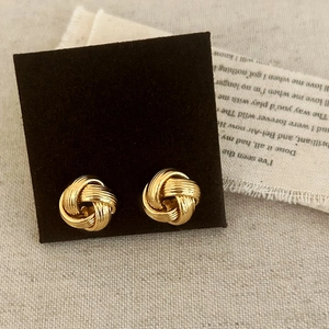 Close-up of golden love knot earrings on a vintage paper and burlap background