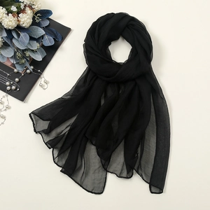 Detail showing the sheer texture of a black 30D chiffon scarf with elegant pearl props
