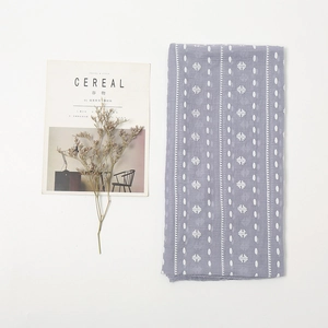 Flat lay of purple linen scarf with white polka dot stars next to a magazine and dried flower