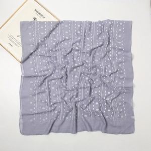Close-up of gray-purple cotton linen scarf with white geometric patterns on white background