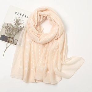 Detail of light beige scarf featuring white textured polka dots and soft geometric weave