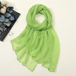 Detailed texture of light green chiffon scarf with pleats and elegant beach accessories