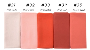 Detail showing folded gradient shades of pearl chiffon scarves from pink nude to brick red