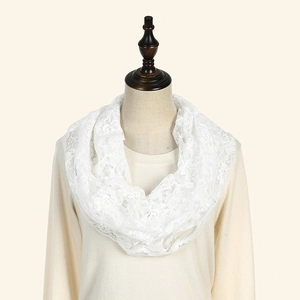 Détail du foulard infini en dentelle blanche avec broderies florales ajourées fines