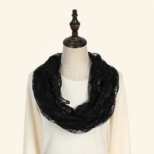 Détail d'un foulard infini en dentelle noire avec broderie florale délicate
