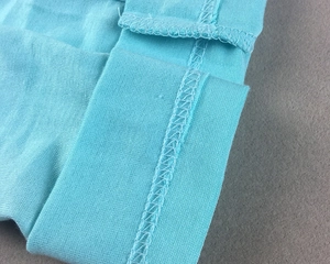 Close-up of sky blue modal fabric showing flat-lock seam stitching and soft texture
