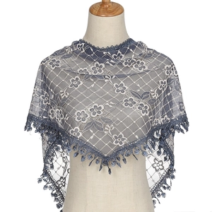 Elegant blue floral lace triangle shawl with delicate fringe on a wooden hanger