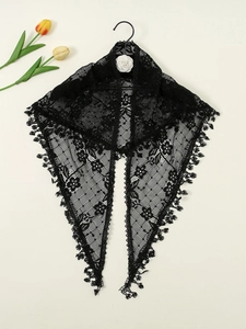 Detail of black floral lace triangle scarf featuring intricate hollow patterns and fringe