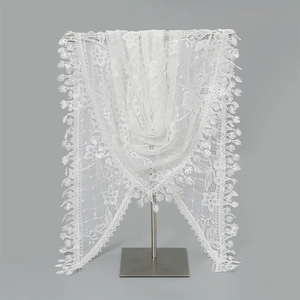 Detail view of white floral lace triangle scarf featuring intricate cutouts and fringe tassels