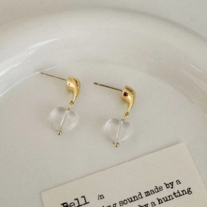 Detail of sweet heart-shaped clear glass drop earrings on a minimalist ceramic plate