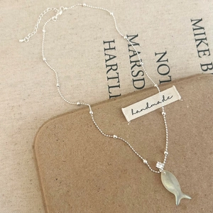 Minimalist silver bead chain necklace featuring a green shell fish pendant and crystal