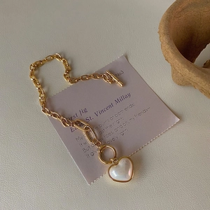 Elegant gold OT buckle heart pendant necklace with mother-of-pearl inlay on artistic background