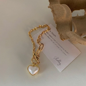 Detail of gold chain bracelet with OT toggle clasp and iridescent heart charm