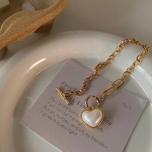 Detailed view of heart charm bracelet with toggle clasp and iridescent shell inlay