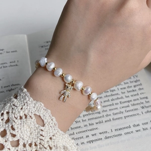 Detailed close-up of a baroque pearl bracelet with a crystal-studded golden bear charm