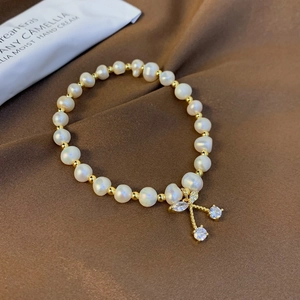 Detailed shot of pearl bracelet with golden cherry pendant and sparkling rhinestones