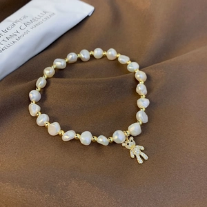 Detailed close-up of a freshwater pearl bracelet with a sparkling gold bear charm pendant