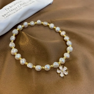 Detail of freshwater pearl bracelet with zircon flower charm on brown silk fabric