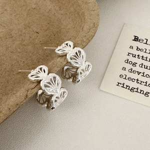 Macro shot of silver hollow heart C-shape earrings displayed on an elegant card
