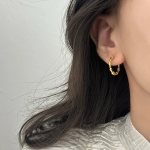Minimalist gold hoop earrings with twisted texture shown on female model ear