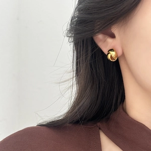 Minimalist gold twist stud earrings with a glossy spiral design worn by a model