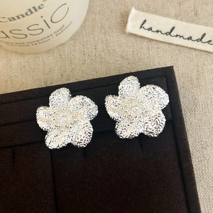 Elegant silver flower earrings with hammered texture on a cozy velvet display box