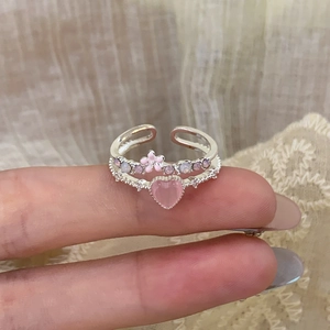 Detail of silver heart ring with pink stone, small flower, and purple side crystals