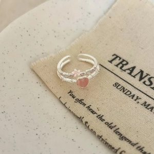 Detail of pink heart gemstone ring with floral accents on a vintage fabric background