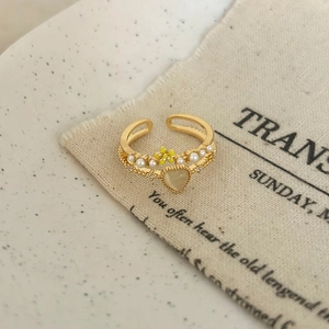Detail of vintage heart opal ring with pearl and flower accents on beige fabric