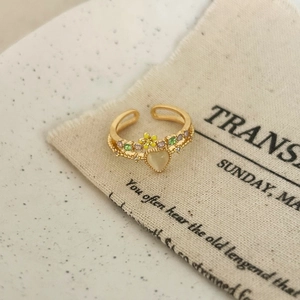 Detail of vintage gold open ring with heart cat-eye stone and enamel floral accents