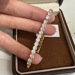 Classic gold-plated tennis bracelet with round cubic zirconia held by hand