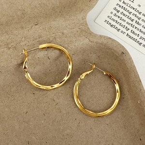 Gros plan de boucles d'oreilles créoles dorées torsadées sur fond de papier kraft