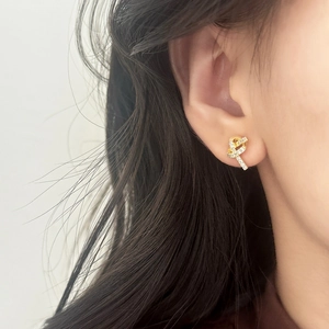 Élégantes boucles d'oreilles nœud dorées avec zircons scintillants sur l'oreille