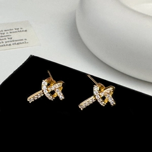 Gros plan de boucles d'oreilles nœud dorées avec zircons étincelants sur support noir
