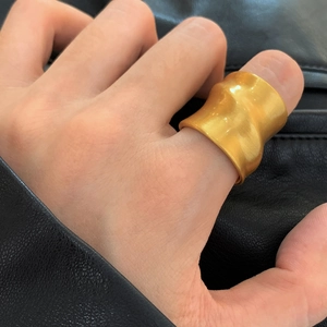 Anello aperto largo dorato con trama a onde e finitura opaca spazzolata su mano