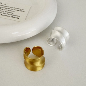Anelli aperti minimalisti opachi oro e argento con texture a onde su sfondo bianco