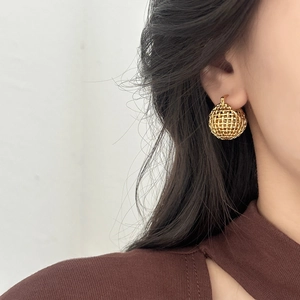 Elegant gold hollow woven sphere drop earrings shown on a model with minimalist design