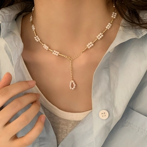 Minimalistische gouden ketting met parelbloemen en hanger bij een vrouw
